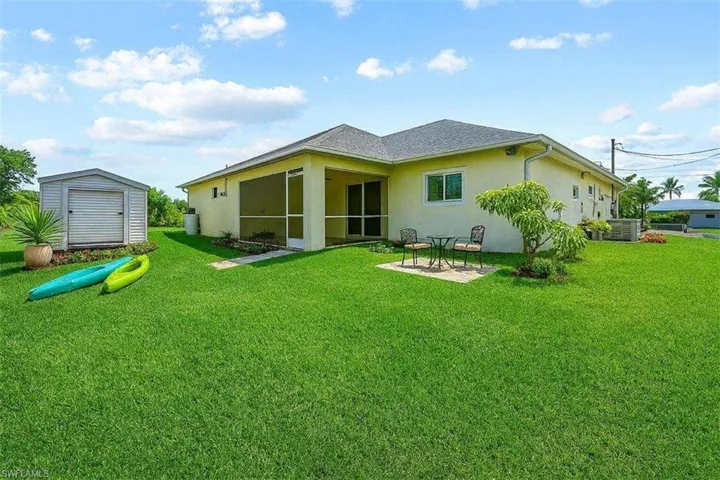Rear view of property with a sunroom, a shed, stucco siding, and a lawn