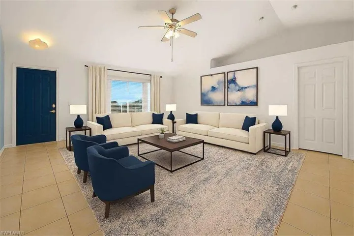 Living area featuring light tile patterned floors, lofted ceiling, and a ceiling fan