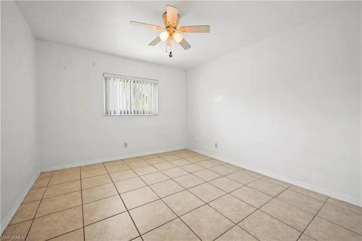 Spare room with a ceiling fan, light tile patterned floors, and baseboards