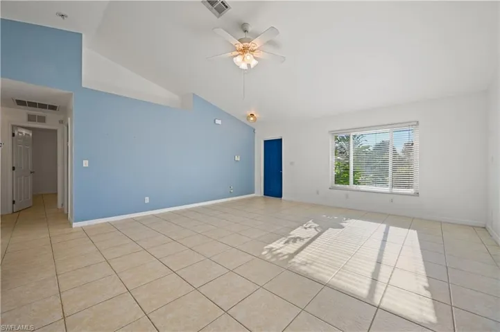 Empty room featuring light tile patterned flooring, a ceiling fan, and high vaulted ceiling