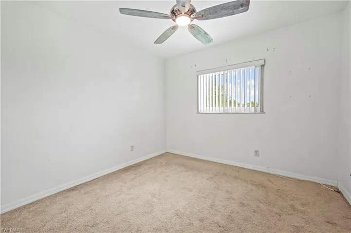 Carpeted empty room with baseboards and a ceiling fan