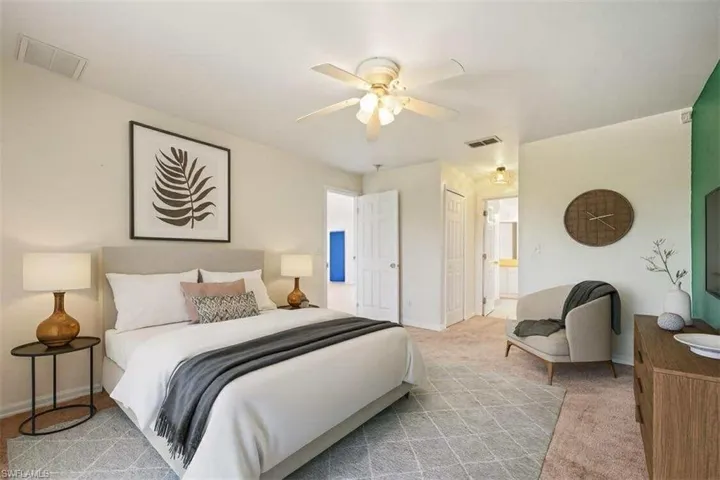 Bedroom featuring light colored carpet, a ceiling fan, connected bathroom, and a closet