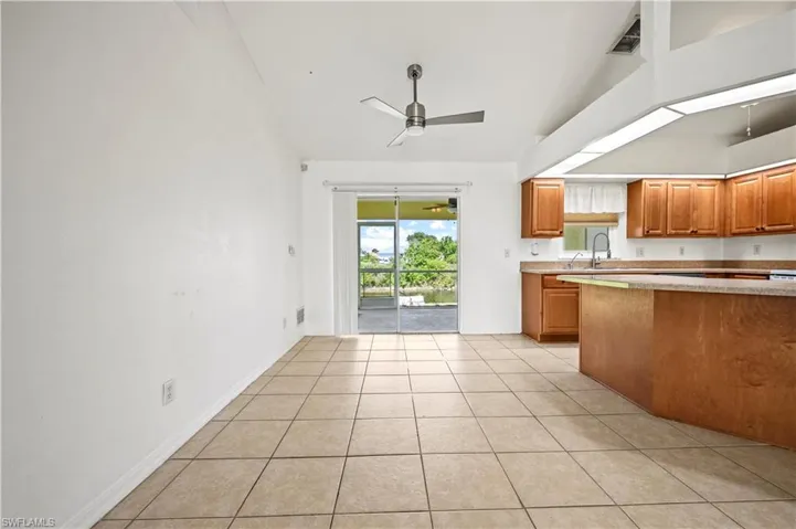 Kitchen with light countertops, ceiling fan, light tile patterned floors, high vaulted ceiling, and brown cabinetry