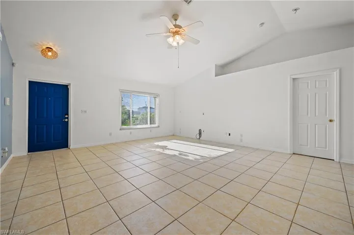 Unfurnished living room featuring light tile patterned floors, a ceiling fan, and high vaulted ceiling