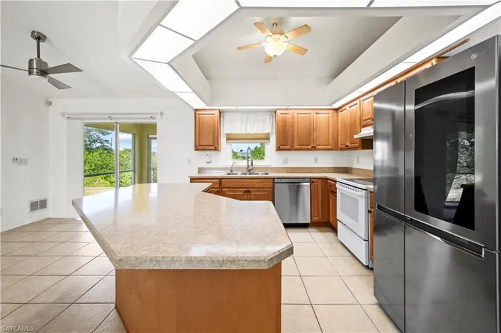 Kitchen featuring appliances with stainless steel finishes, a ceiling fan, light tile patterned floors, and a sink
