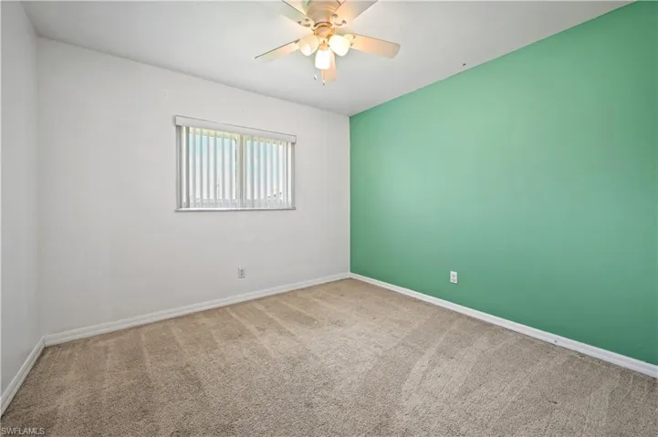 Carpeted spare room with baseboards and a ceiling fan