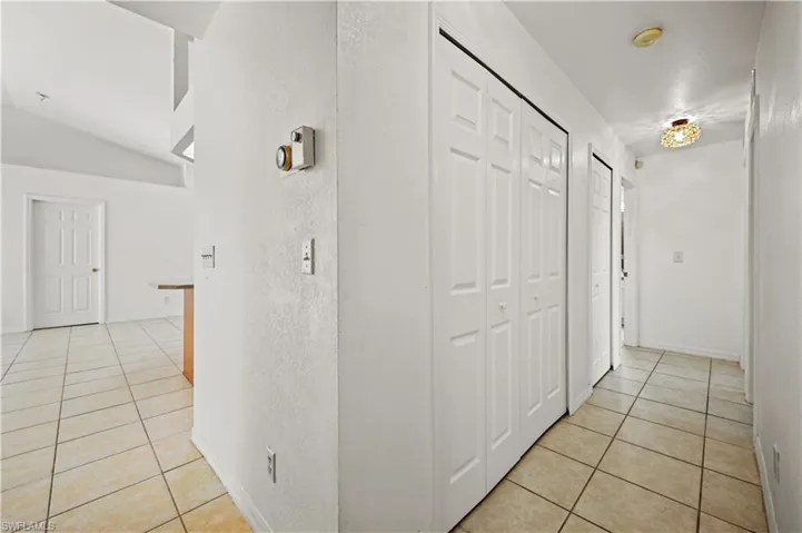 Hall with light tile patterned floors and lofted ceiling
