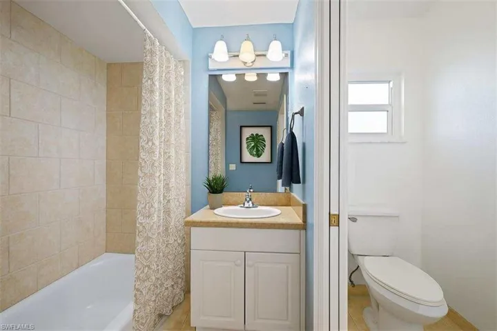Bathroom featuring shower / bath combination with curtain and vanity