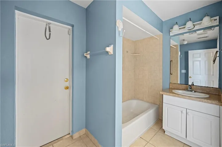 Bathroom featuring light tile patterned flooring, shower / bath combination, and vanity