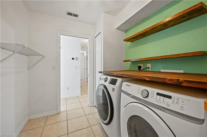 Laundry room featuring washing machine and clothes dryer and light tile patterned floors