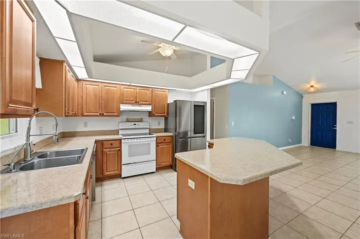 Kitchen with electric stove, a sink, ceiling fan, smart refrigerator, and vaulted ceiling