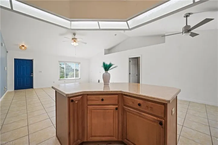 Kitchen with a ceiling fan, light countertops, light tile patterned floors, lofted ceiling, and open floor plan