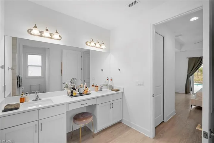 Bathroom featuring healthy amount of natural light, double vanity, light wood-type flooring, ensuite bath, and recessed lighting