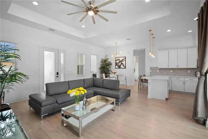 Living room featuring ceiling fan, recessed lighting, light wood-type flooring, and a tray ceiling