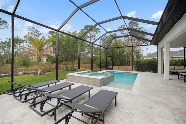Integrated pool / hot tub featuring a sunroom, a patio area, glass enclosure, and a lawn