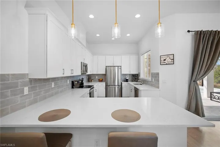 Kitchen with a kitchen breakfast bar, light stone countertops, and a peninsula
