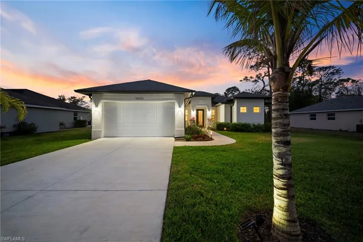 View of front of home featuring a front lawn, a garage, concrete driveway, and stucco siding