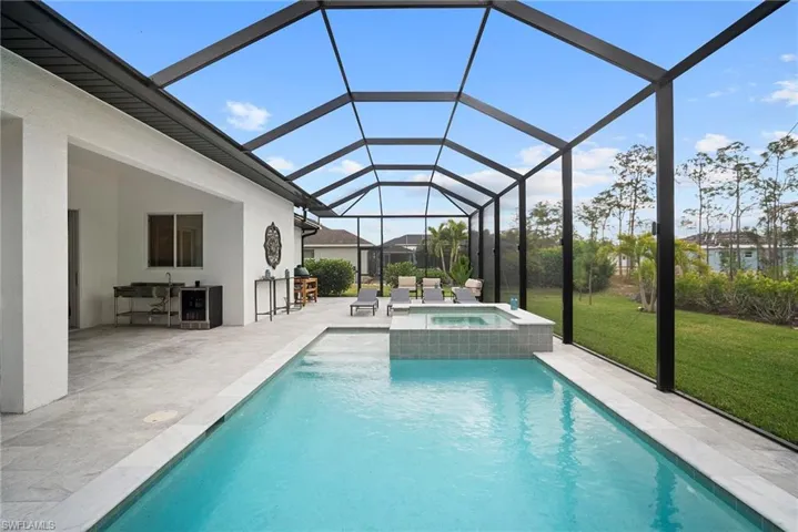 Combined pool / hot tub with a lawn, a sunroom, a patio, and a lanai