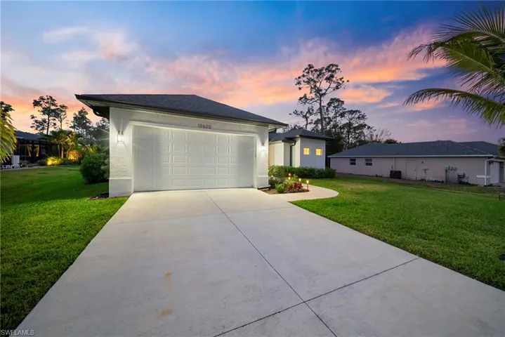 View of front of property featuring a lawn, concrete driveway, stucco siding, and a garage