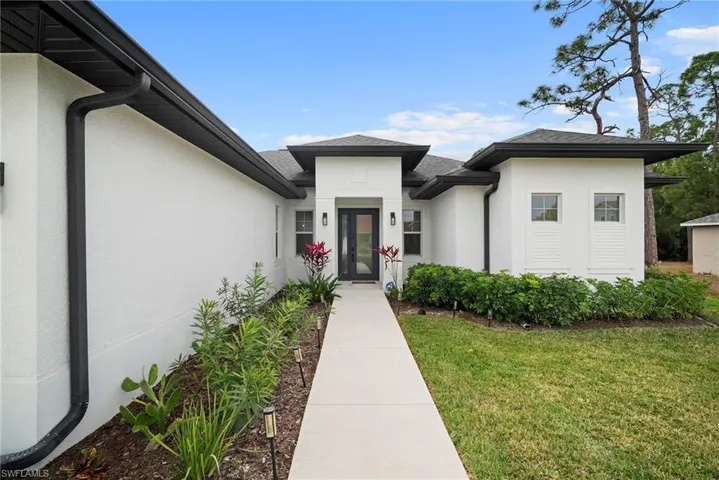 Doorway to property featuring a lawn and stucco siding