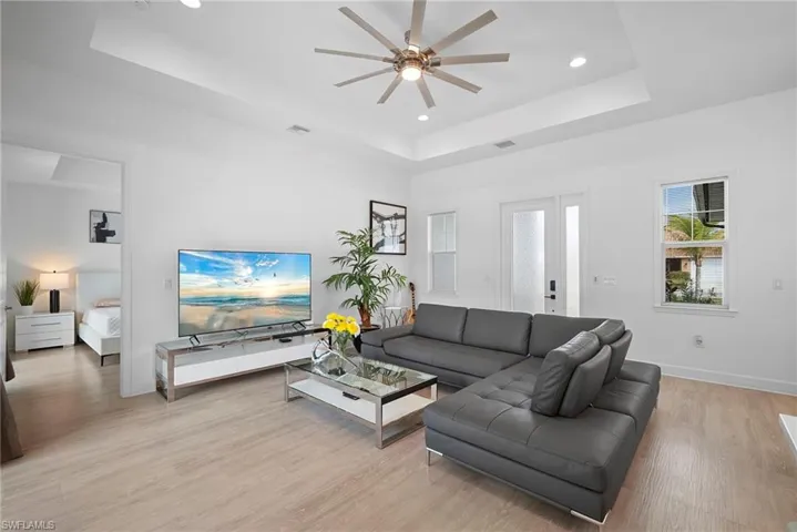 Living room with light wood finished floors, ceiling fan, and recessed lighting