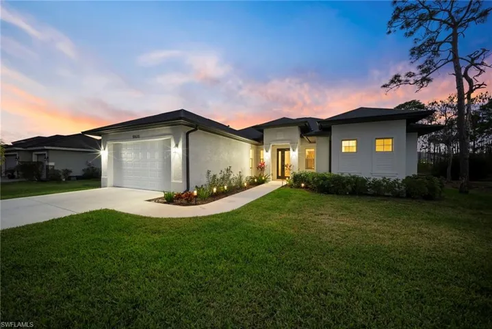 View of front of property with stucco siding, a lawn, driveway, and a garage