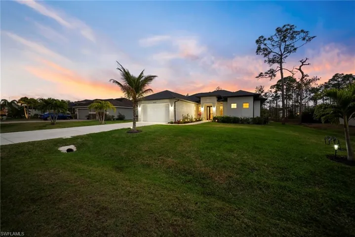 View of front facade with concrete driveway, a yard, stucco siding, and a garage