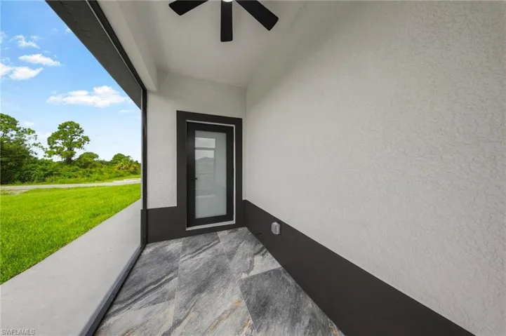 Screened lanai with textured walls, ceiling fan, and gray large format tile flooring