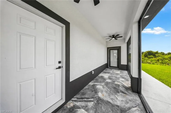 Covered patio featuring patterned tile flooring, a ceiling fan, recessed lighting, and a sliding glass door