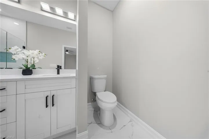 White vanity with a solid surface countertop, undermount sink, and matte black faucet
