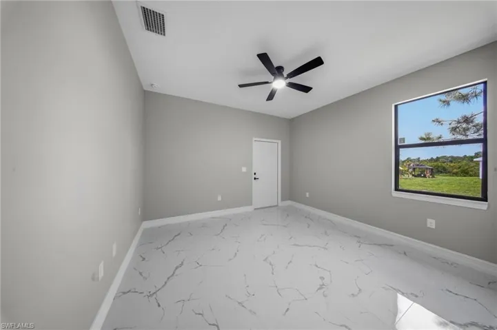 Spacious room with light gray walls, large window, and marbled tile flooring