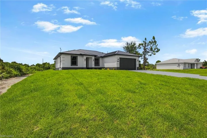 Contemporary exterior architecture with a dark metal roof, a full two-car garage, and a concrete driveway