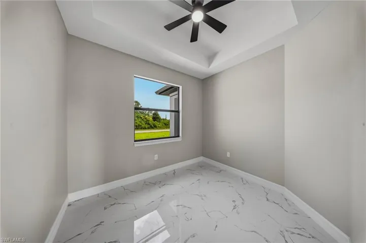 Tray ceiling with a ceiling fan, light gray wall paint, single window, and large format tile flooring