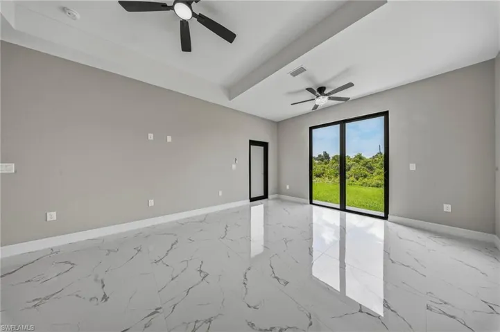 Spacious interior featuring large format tile flooring, a tray ceiling, and dual ceiling fans