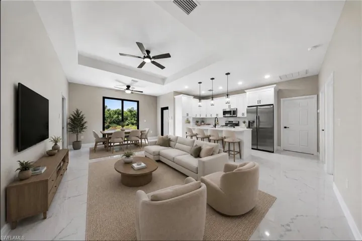 Open-concept living space featuring polished stone flooring, a coffered ceiling with ceiling fan, and recessed lighting throughout