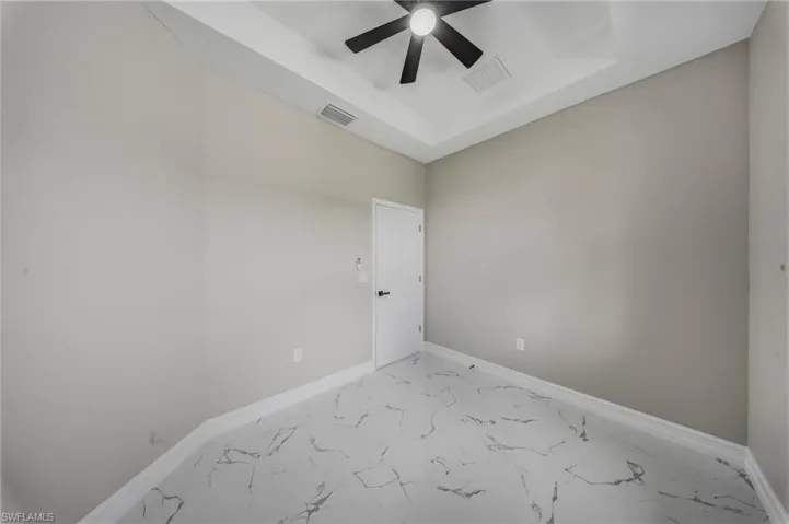 Tray ceiling, contemporary ceiling fan with light, light-toned walls, white trim, and marble-look flooring