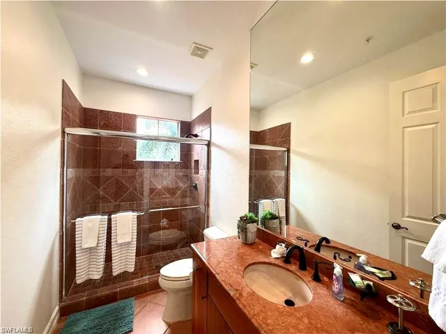 Full bath featuring vanity, a shower stall, light tile patterned floors, and a textured wall