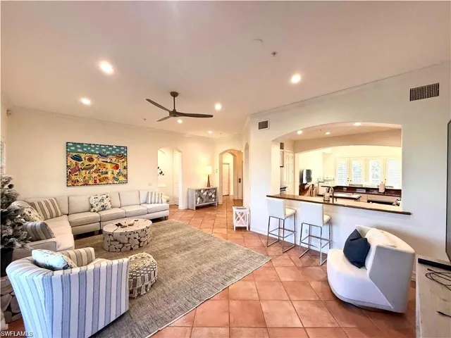 Living room featuring arched walkways, light tile patterned flooring, recessed lighting, ceiling fan, and crown molding