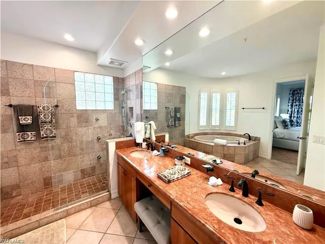 Ensuite bathroom featuring light tile patterned flooring, double vanity, walk in shower, a bath, and recessed lighting