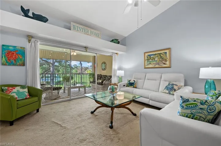 Carpeted living area with ceiling fan and high vaulted ceiling