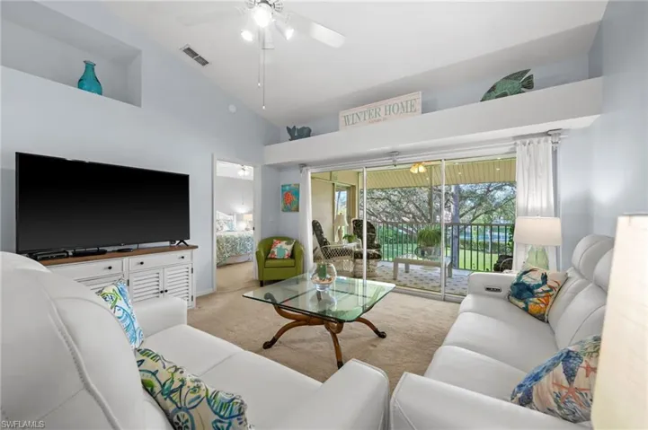 Carpeted living room featuring high vaulted ceiling and a ceiling fan