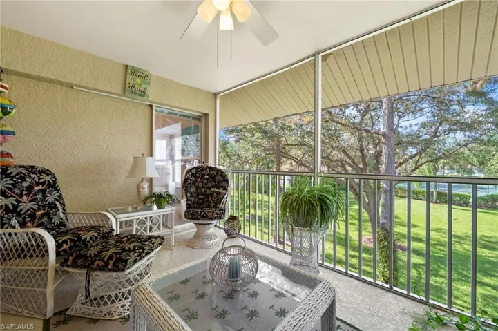 Sunroom / solarium featuring a textured wall, ceiling fan, and a balcony