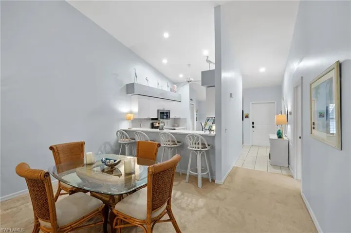 Dining space featuring light carpet, recessed lighting, vaulted ceiling, and light tile patterned flooring