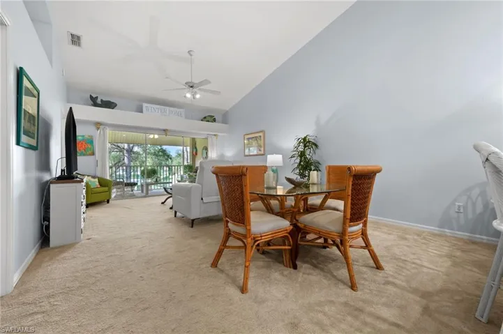 Dining space with high vaulted ceiling, light colored carpet, and ceiling fan