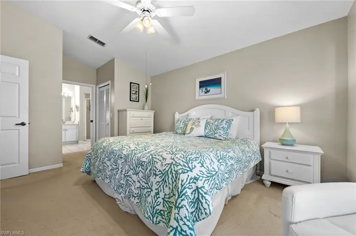 Bedroom with light carpet, a closet, a ceiling fan, and connected bathroom