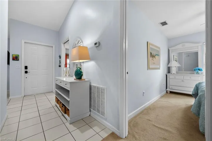 Entryway with light tile patterned floors and light carpet