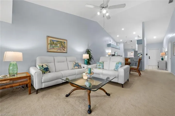 Carpeted living room featuring a ceiling fan and lofted ceiling
