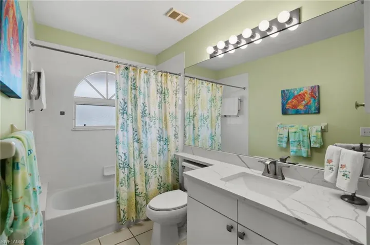 Full bath with shower / tub combo with curtain, vanity, and light tile patterned flooring