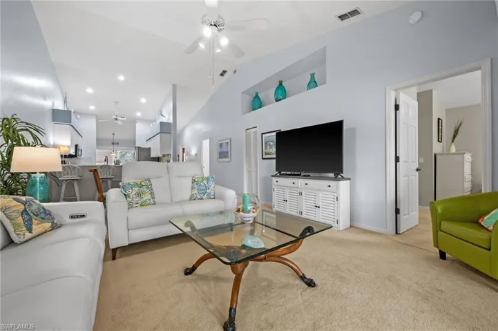Carpeted living area with ceiling fan, recessed lighting, and high vaulted ceiling