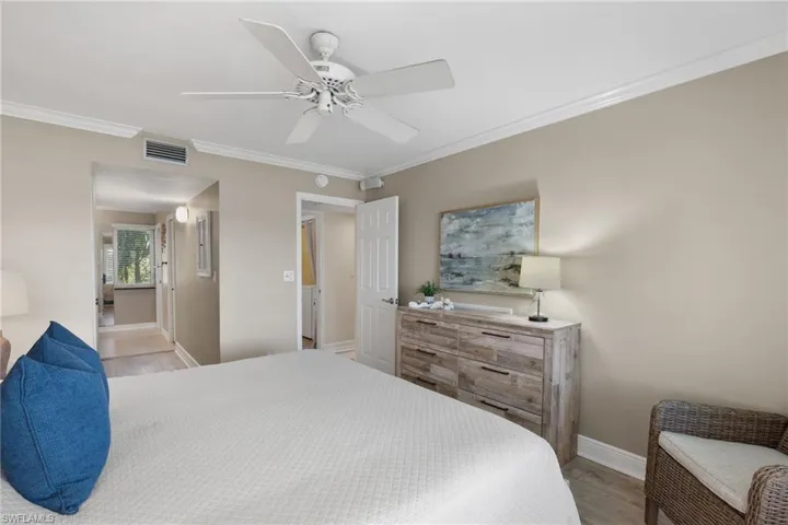 Bedroom with ornamental molding, a ceiling fan, and light wood-style floors